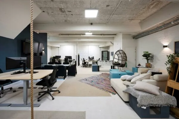 Modern en creatief ingericht kantoor aan de James Wattstraat met bureaus, loungehoek, hangstoel en tafelvoetbaltafel.